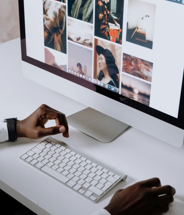 Man working on computer in modern office, viewing photography website. Clean and tech-focused environment.